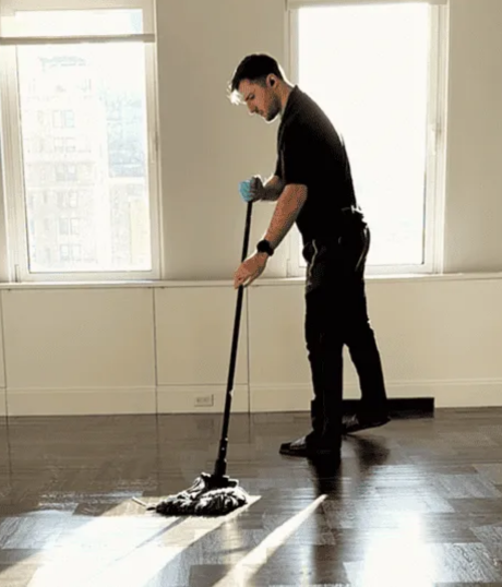 Professional cleaner mopping floor with wet mop during home cleaning service