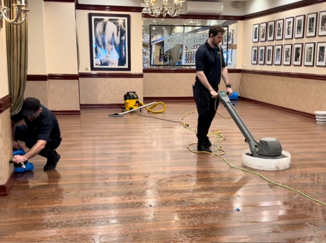 oor care experts buffing hardwood floors to a glossy, polished finish in a luxury Manhattan space using high-end equipment.