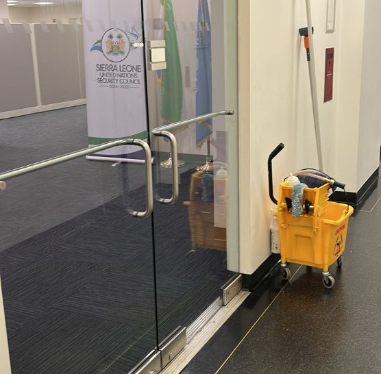 Bucket with professional cleaning supplies placed outside a freshly cleaned office space