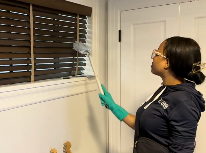 Professional house cleaner expertly cleaning window blind