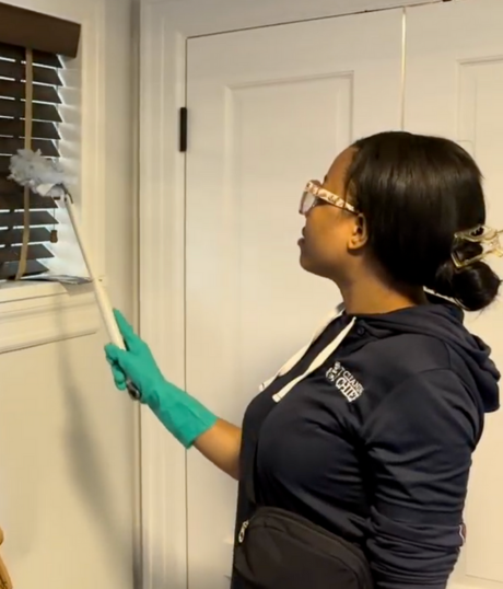 Housekeeping maid gently dusting interior window surfaces. Daily residential cleaning for a brighter, healthier home.