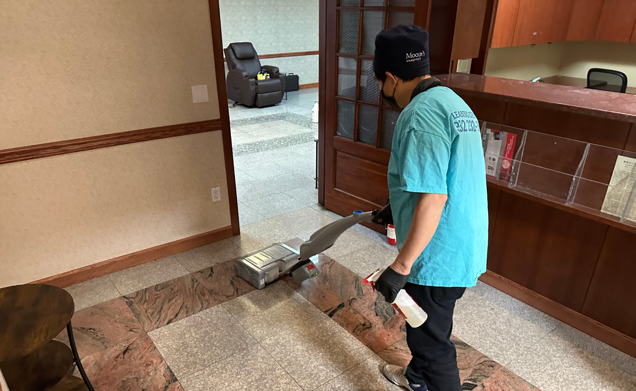 Professional cleaner using floor buffing machine on stone flooring in medical office